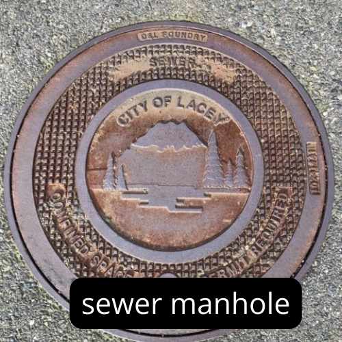 brown metal round sewer manhole cover with CIty of Lacey logo