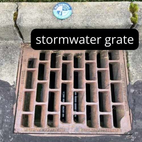 square brown metal stormwater grate next to curb 